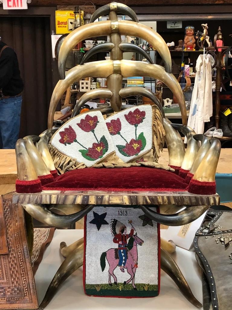 Antique chair made of steer horns with red velvet seat, beaded floral bags, and a 1913 Native American beaded panel at a CCG vendor booth