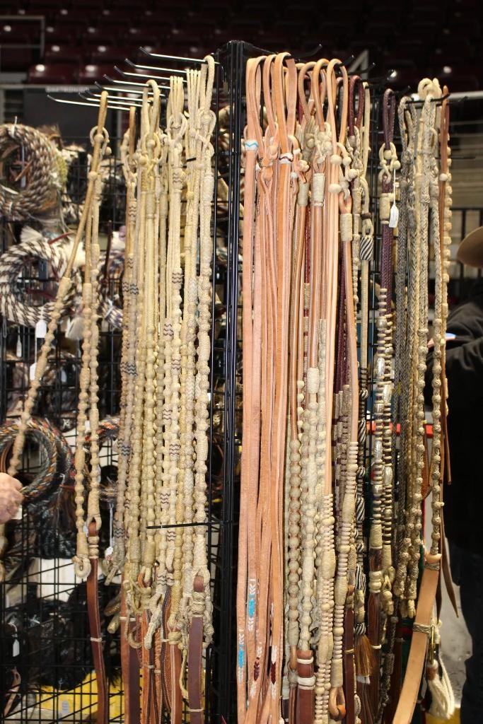 Rack of braided leather reins and rawhide ropes at a vendor booth