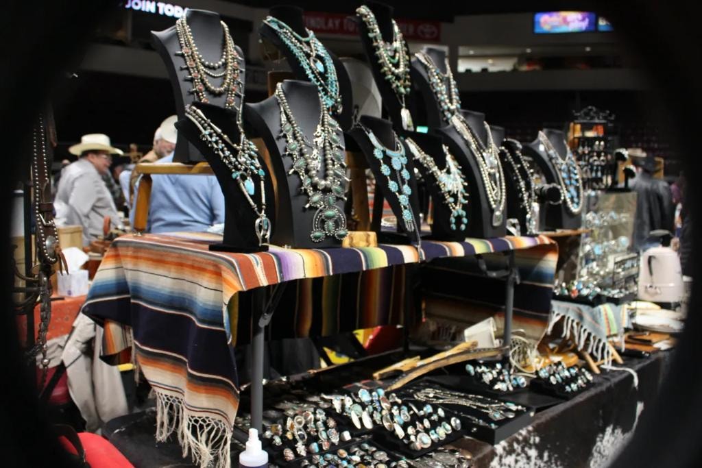 Squash blossom necklaces and turquoise jewelry on mannequin busts with striped serape blankets