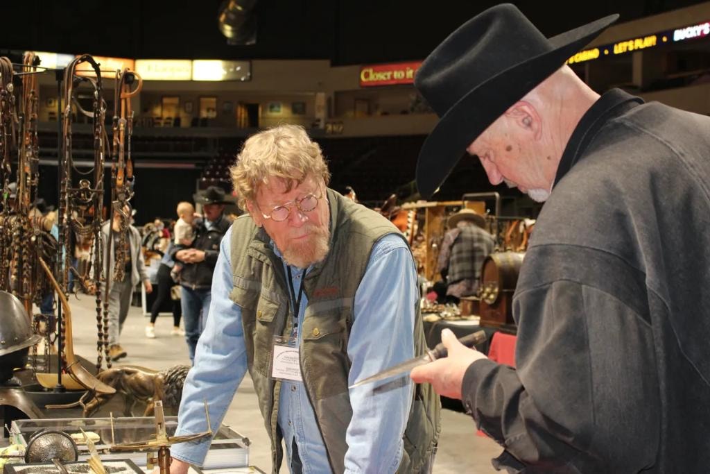 Two collectors examining an antique knife at a vendor booth