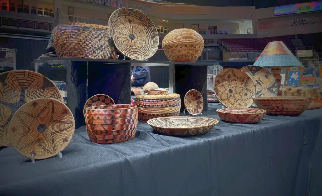 Large collection of colorful woven baskets and vessels on display table
